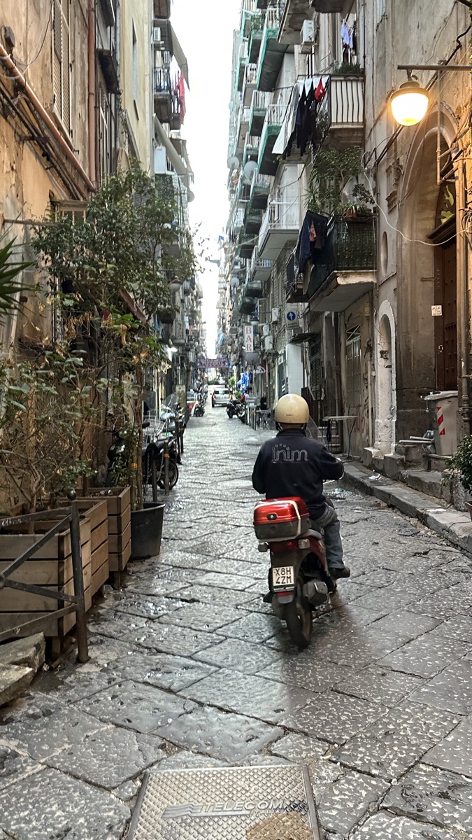 A scooter riding through the streets of Naples